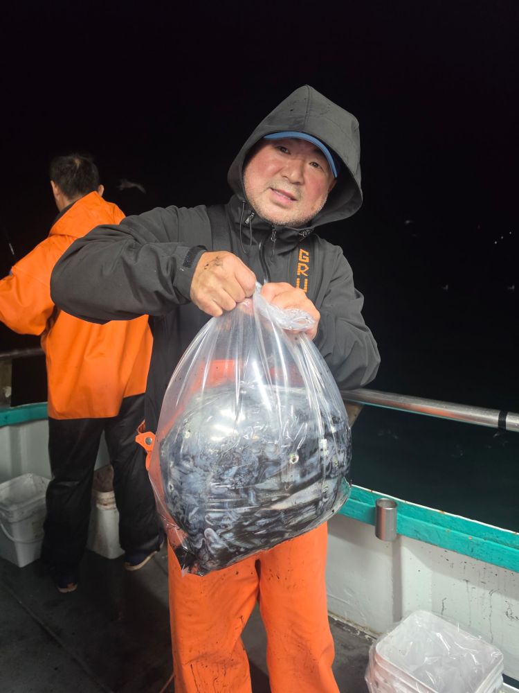 Person on a boat holding a bag of fish at night.