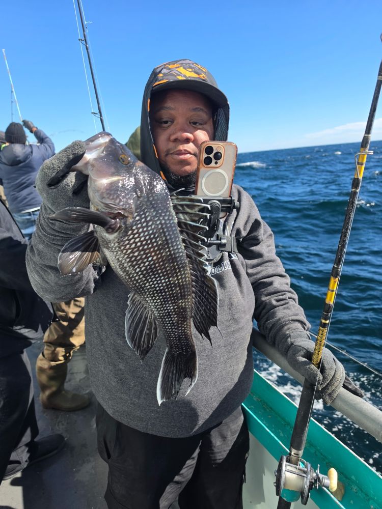 Person holding fish on boat with ocean in background.