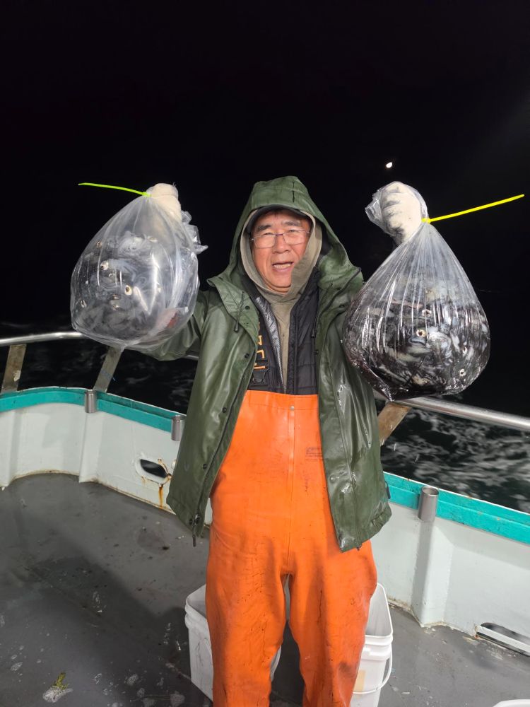 Person holding bags of fish on a boat at night.