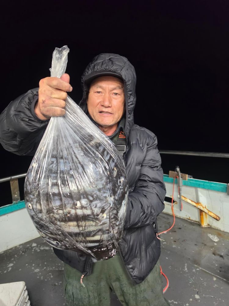 Person holding a clear plastic bag full of fish on a boat