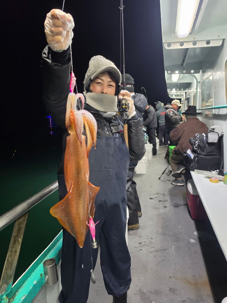 Person on boat at night holding a large squid on a fishing line.
