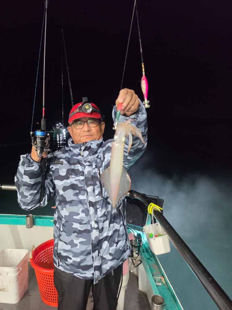 Person on boat holding a large squid at night.