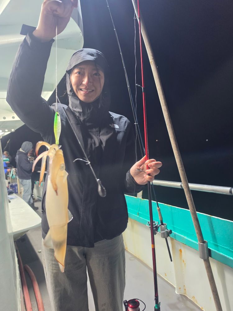 Person on boat holding a squid and fishing rod at night.