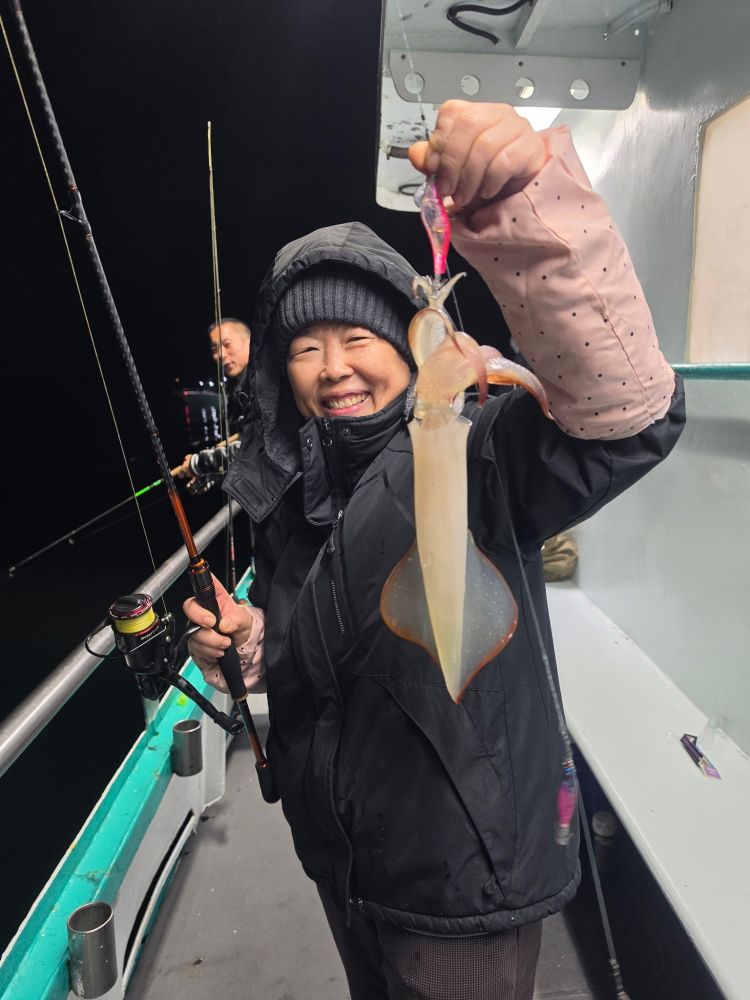 Person on a boat at night holding a squid with fishing rod.