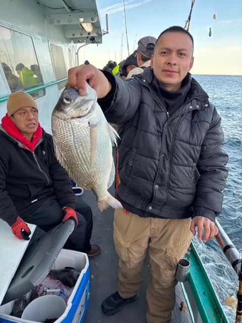 Man holding a fish on a boat with others in the background.