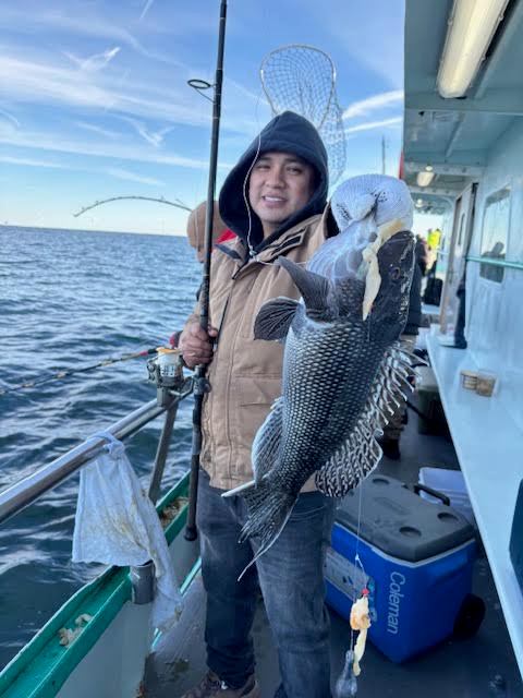 Person on a boat holding a fishing rod and a large fish.