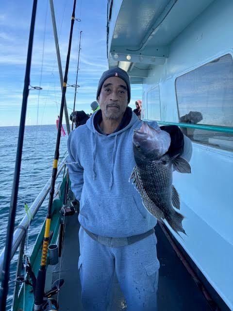 Person in gray outfit holding a fish on a boat.