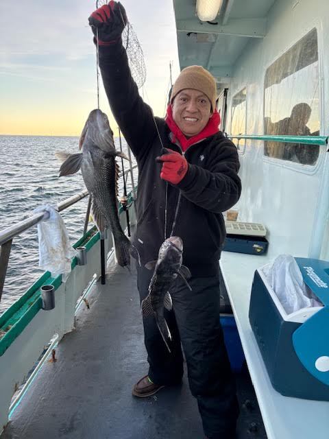 Person holding two fish on a boat deck.