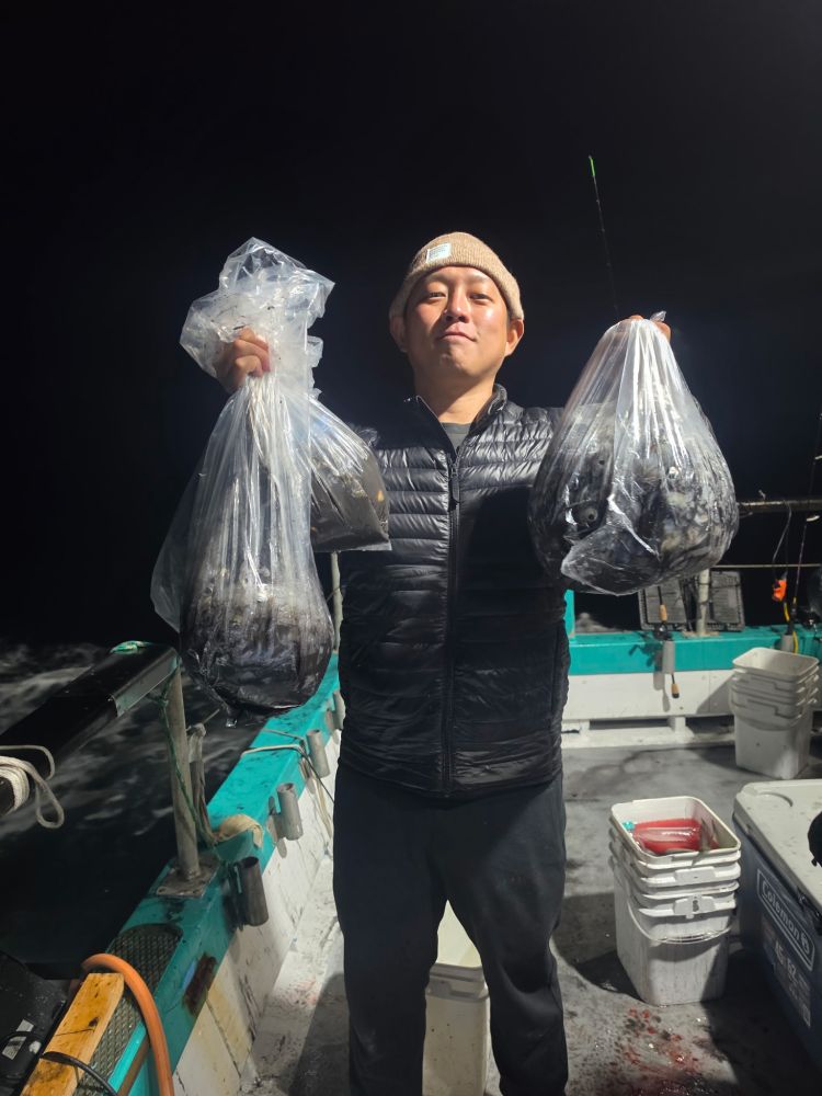 Person holding two bags of fish on a boat at night.