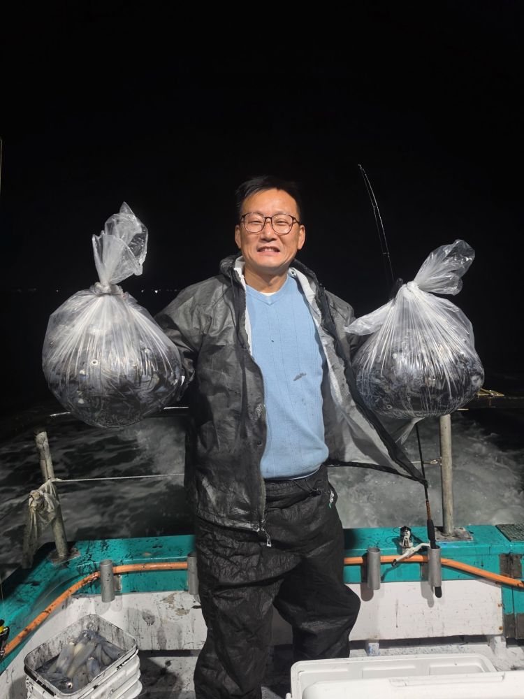 Person on a boat holding two bags of fish at night.