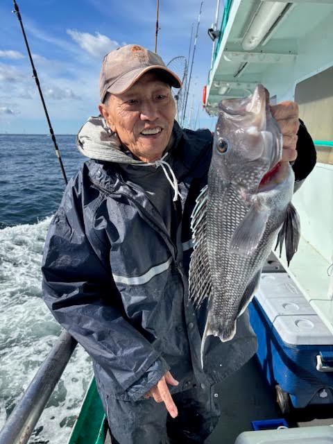 Person on a boat holding a large fish with ocean in the background.