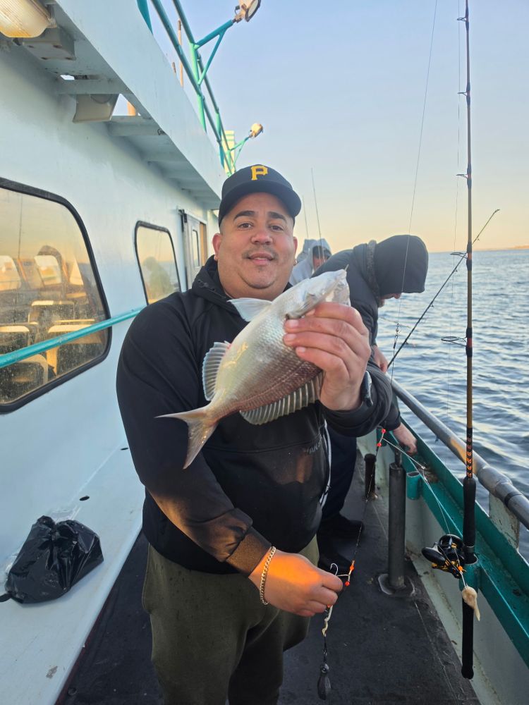 Man holding a fish on a boat while fishing with others.