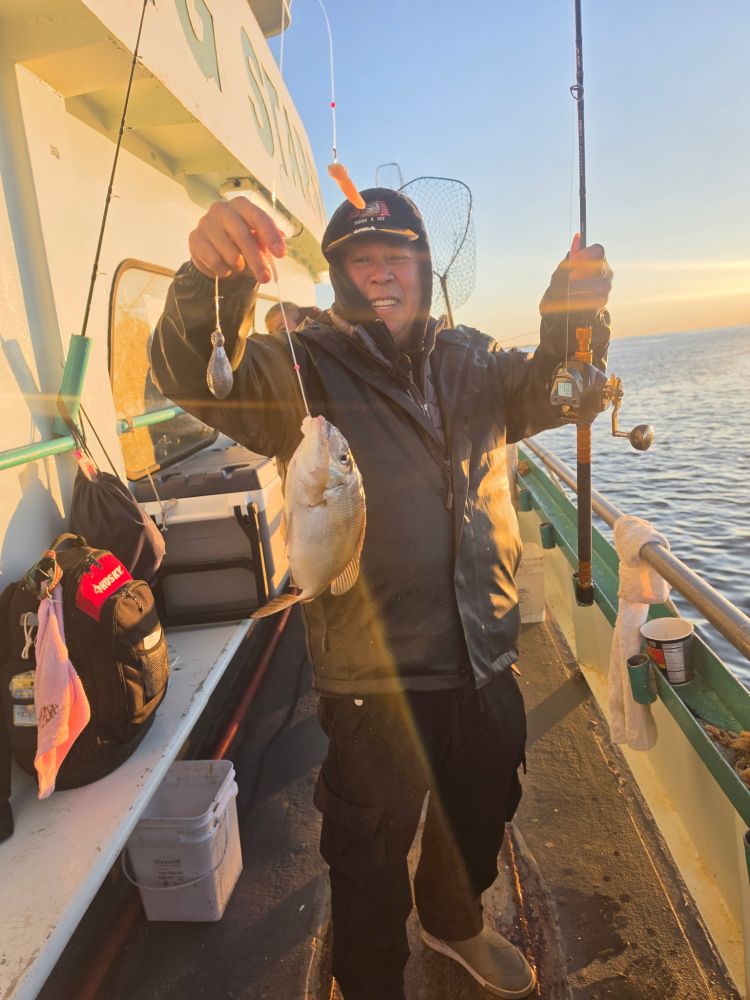 Person on boat holding a fish with fishing rod.