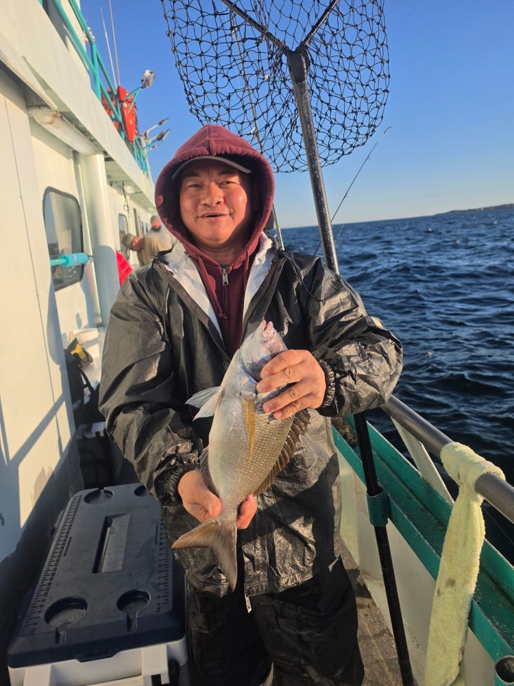 Person on a boat holding a fish with a fishing net in the background.