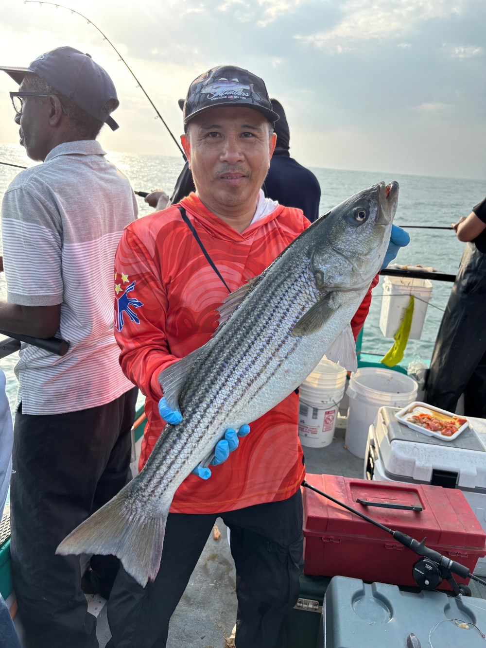 Person in red shirt holding a large fish on a boat.