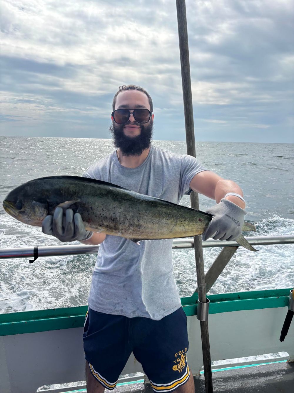 Person on a boat holding a large fish, ocean in the background.