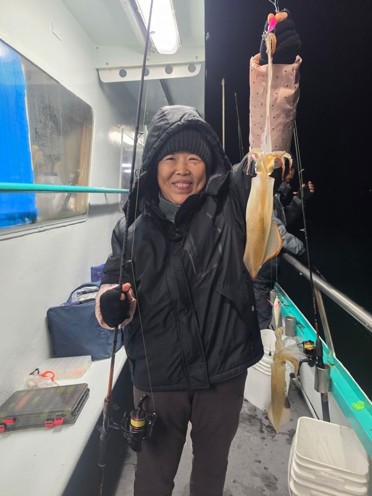 Person on boat holding a squid at night.