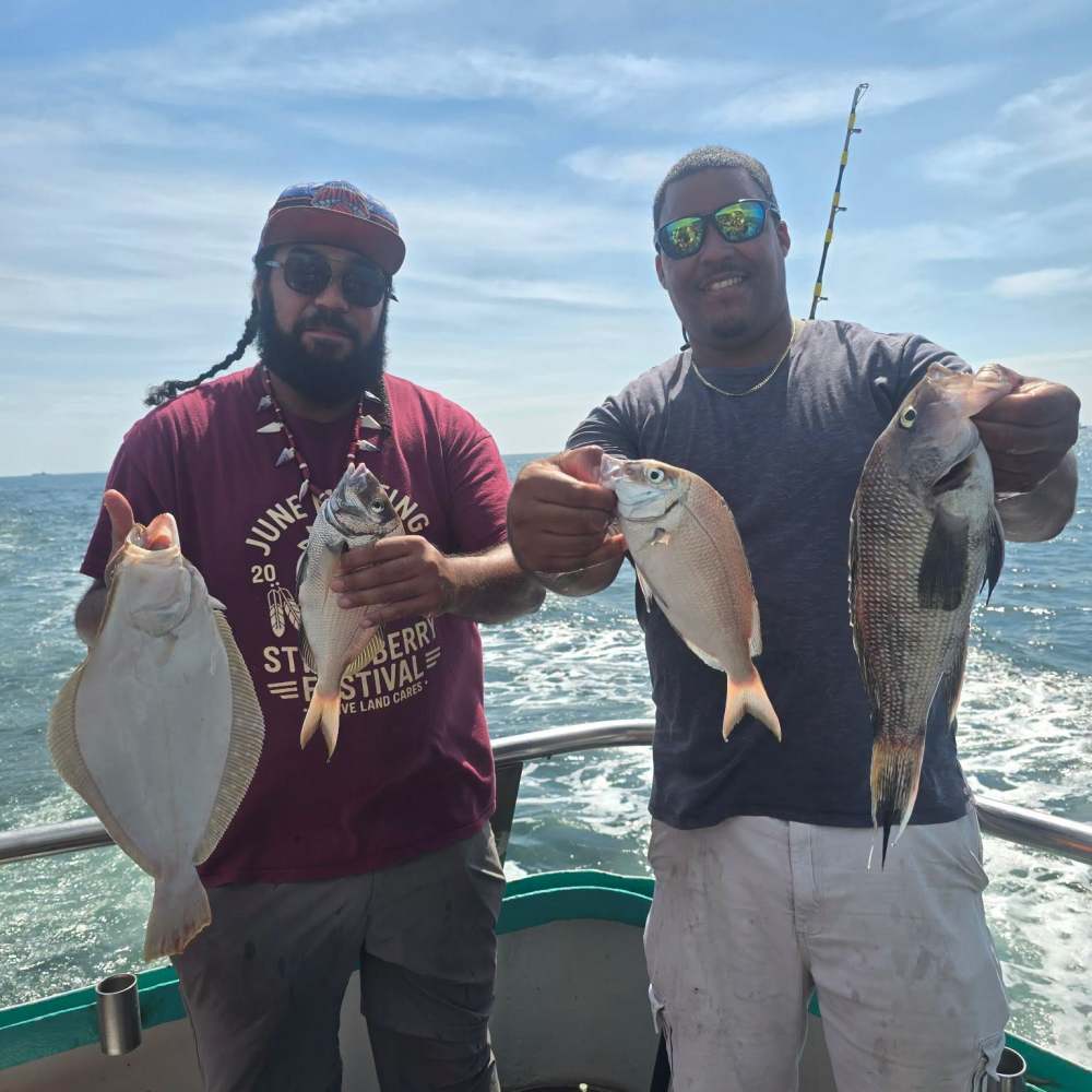 Two men on a boat holding up their catch of fish.