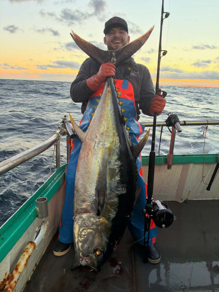 Person on boat holding large fish at sunset.