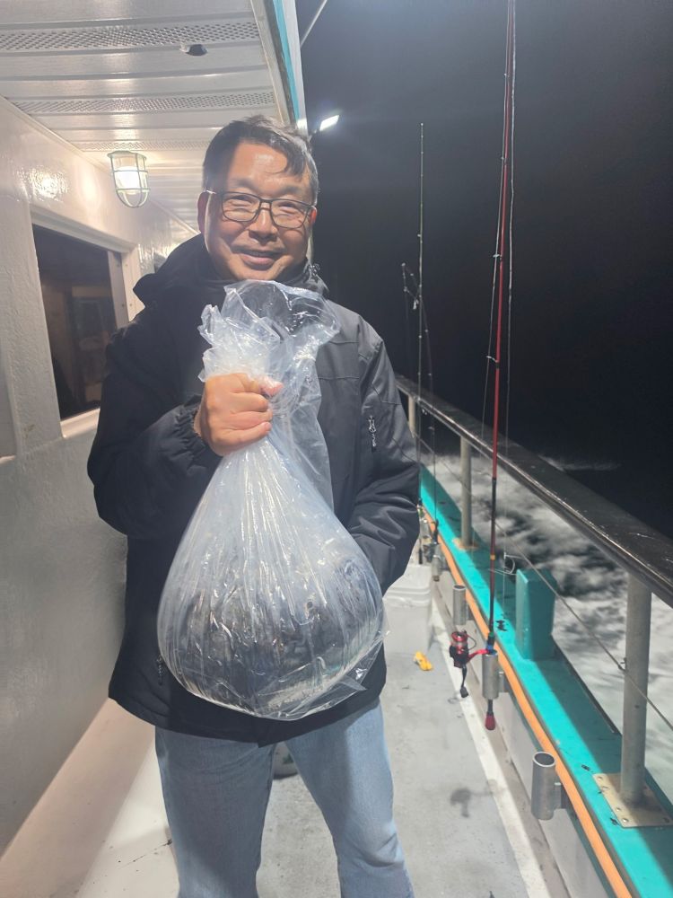 Man on boat holding a large plastic bag at night.