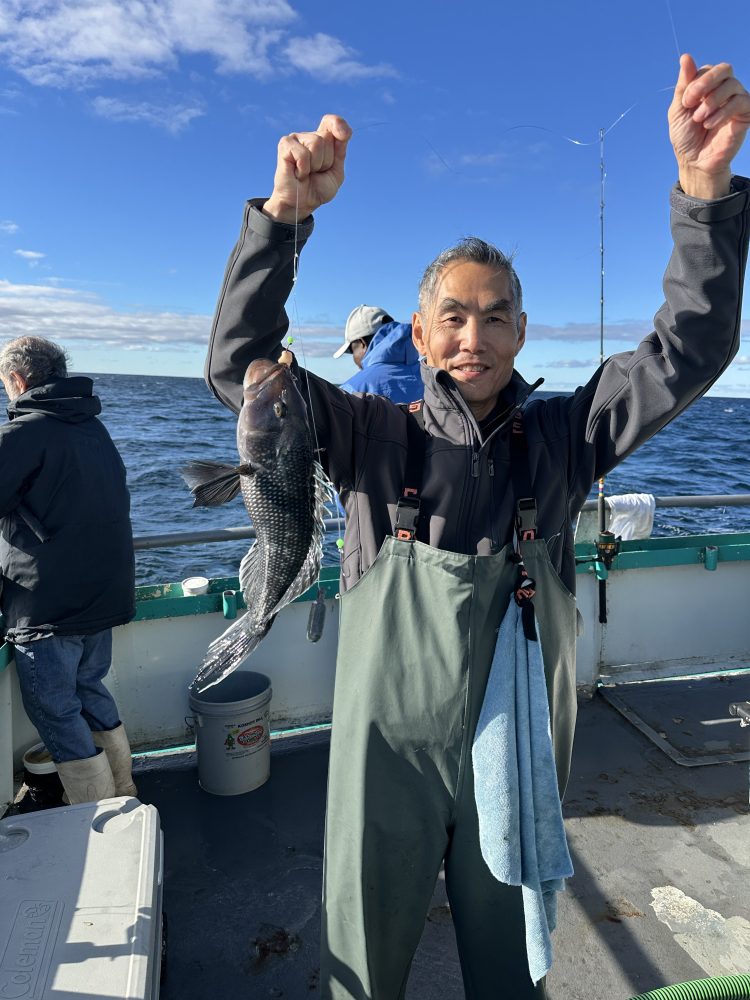 Person on a boat holding a fish with an ocean backdrop.