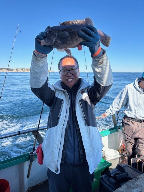 Person on a boat holding a fish, ocean in the background.